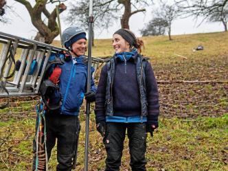 Zwei Baumpflegerinnen in Montur mit Leiter und Ausrüstung auf der Wiese